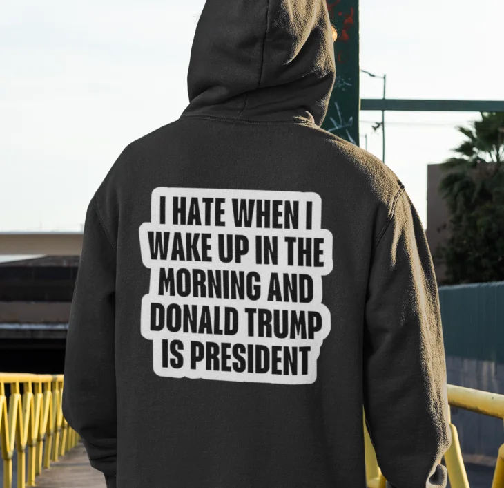 model wearing black hoodie with anti-trump design